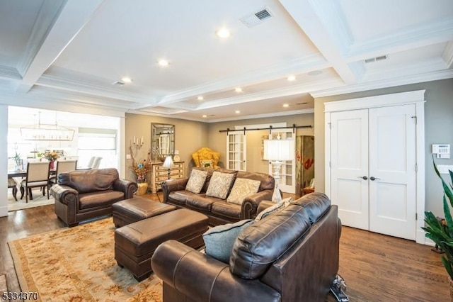 living room featuring beamed ceiling, ornamental molding, a barn door, and dark hardwood / wood-style floors