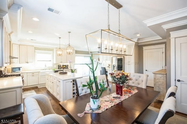 dining room featuring crown molding, dark hardwood / wood-style floors, a chandelier, and sink