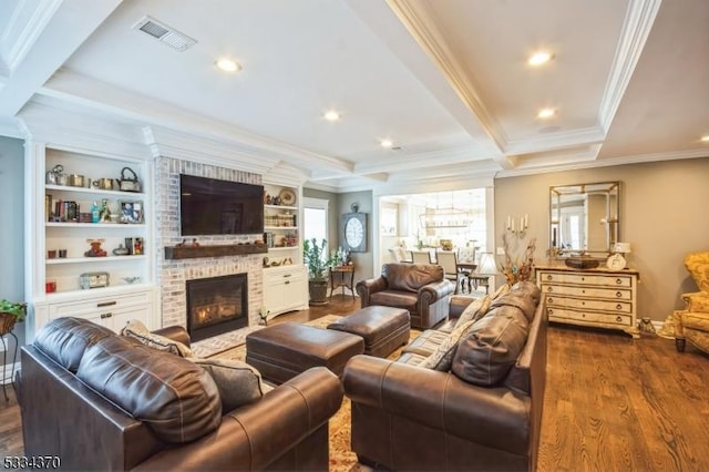 living room with crown molding, built in features, dark hardwood / wood-style flooring, a brick fireplace, and beamed ceiling