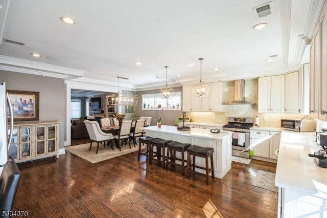 kitchen with wall chimney exhaust hood, a breakfast bar area, stainless steel range, dark hardwood / wood-style flooring, and a kitchen island