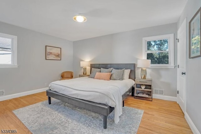 bedroom with multiple windows and hardwood / wood-style floors