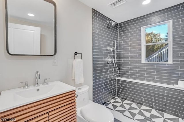 bathroom featuring vanity, a tile shower, and toilet