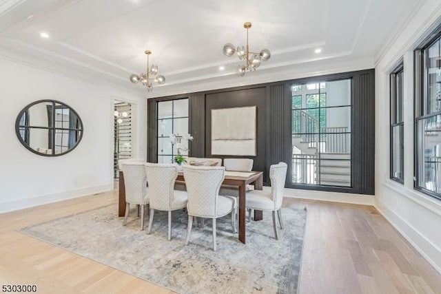 dining area featuring a raised ceiling, an inviting chandelier, and light hardwood / wood-style flooring