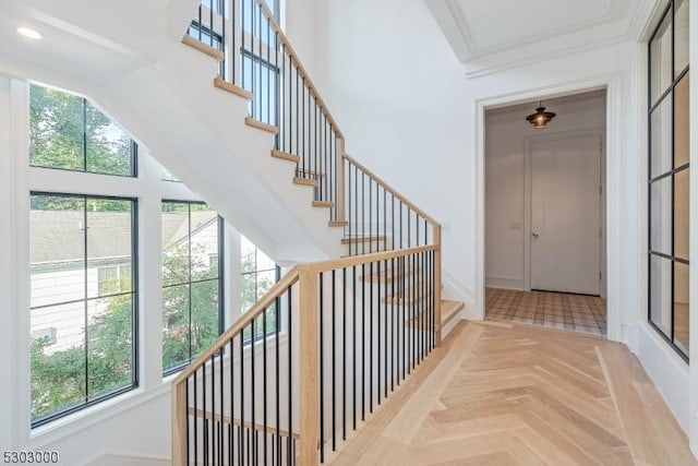 stairs with parquet flooring and ornamental molding