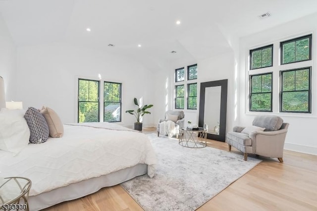 bedroom featuring multiple windows, a high ceiling, and light hardwood / wood-style flooring