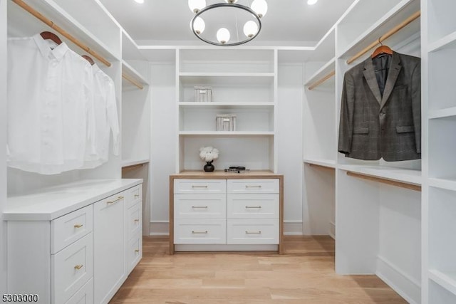 spacious closet with an inviting chandelier and light wood-type flooring