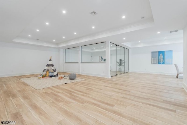 workout room featuring a raised ceiling and light wood-type flooring