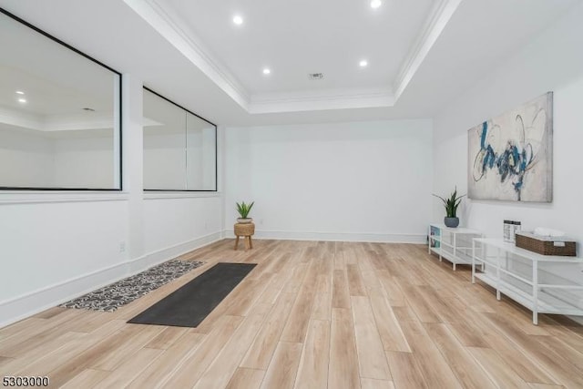 interior space featuring a raised ceiling, crown molding, and light hardwood / wood-style floors