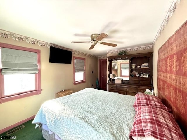 bedroom with multiple windows, ceiling fan, and carpet