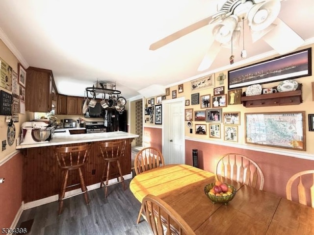 dining space with crown molding, dark wood-type flooring, and ceiling fan