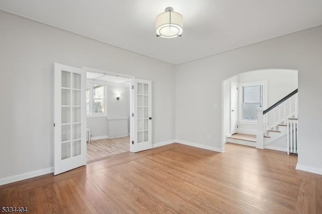 unfurnished room with french doors, wood-type flooring, and radiator heating unit