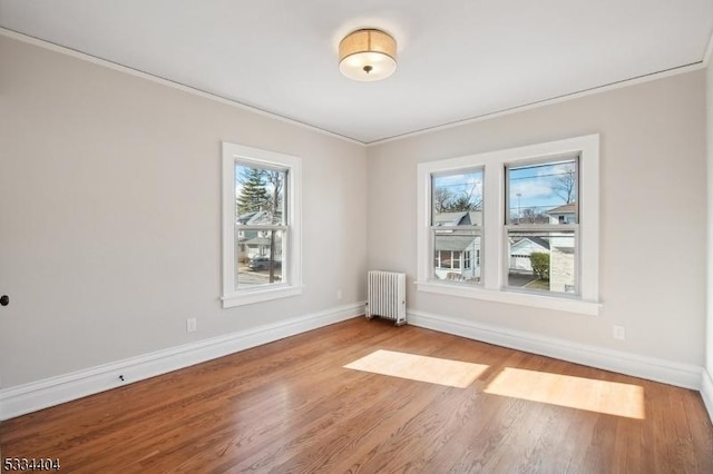 spare room featuring hardwood / wood-style flooring, radiator heating unit, and ornamental molding