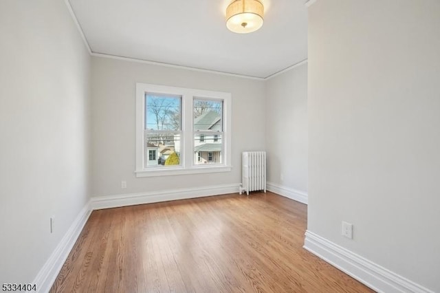 spare room featuring ornamental molding, radiator, and light hardwood / wood-style floors