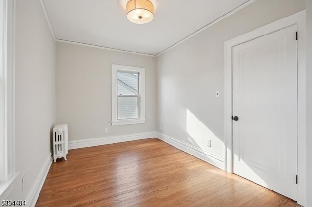 unfurnished room featuring crown molding, radiator, and light hardwood / wood-style flooring