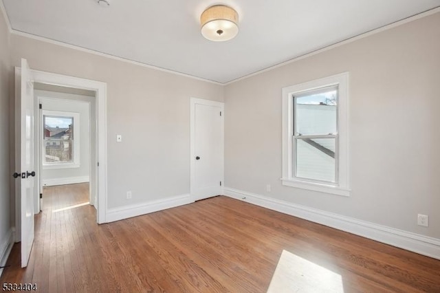 empty room featuring crown molding, a wealth of natural light, and light hardwood / wood-style floors