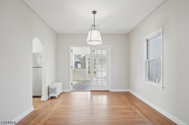 unfurnished dining area featuring radiator and light wood-type flooring