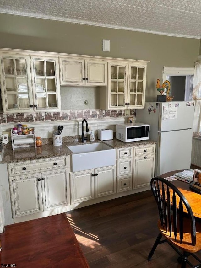 kitchen featuring sink, white appliances, ornamental molding, white cabinets, and dark stone counters