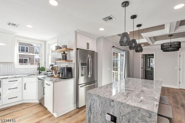 kitchen featuring appliances with stainless steel finishes, white cabinetry, sink, light stone countertops, and light hardwood / wood-style flooring