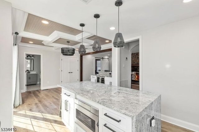 kitchen with white cabinetry, beam ceiling, coffered ceiling, decorative light fixtures, and light wood-type flooring