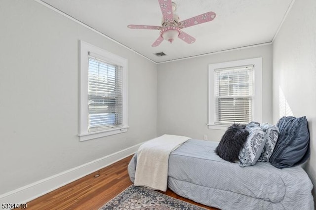 bedroom with crown molding, hardwood / wood-style flooring, and ceiling fan