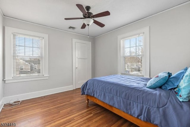 bedroom featuring ceiling fan, ornamental molding, hardwood / wood-style floors, and multiple windows