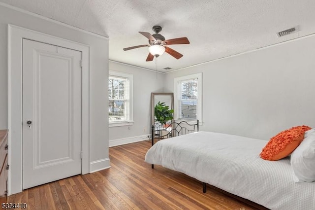 bedroom featuring ceiling fan, wood-type flooring, and a textured ceiling