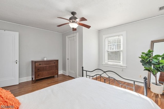 bedroom featuring ceiling fan, dark hardwood / wood-style flooring, and a textured ceiling