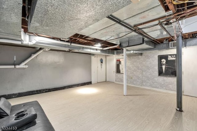 basement featuring brick wall and light wood-type flooring