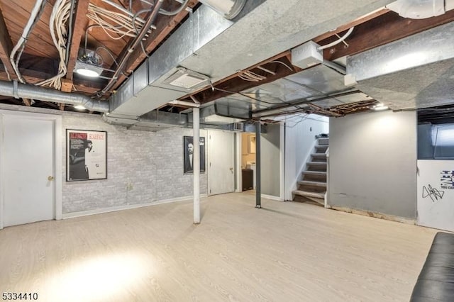 basement featuring hardwood / wood-style floors and brick wall