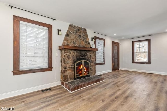 unfurnished living room featuring a stone fireplace and wood-type flooring