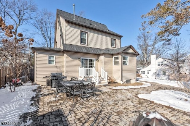 snow covered rear of property with a patio area