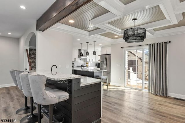 kitchen featuring stainless steel refrigerator with ice dispenser, white cabinetry, decorative light fixtures, light hardwood / wood-style flooring, and ornamental molding