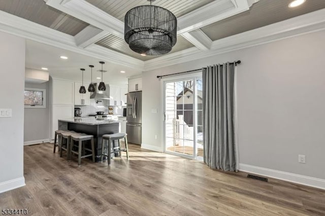 dining area with crown molding, wood-type flooring, coffered ceiling, and beamed ceiling