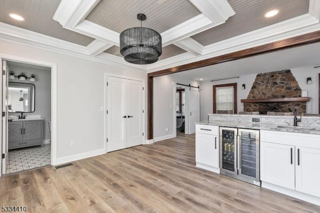 kitchen featuring sink, white cabinetry, a barn door, decorative light fixtures, and beverage cooler