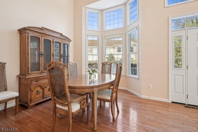 dining area with hardwood / wood-style floors, a high ceiling, and a wealth of natural light