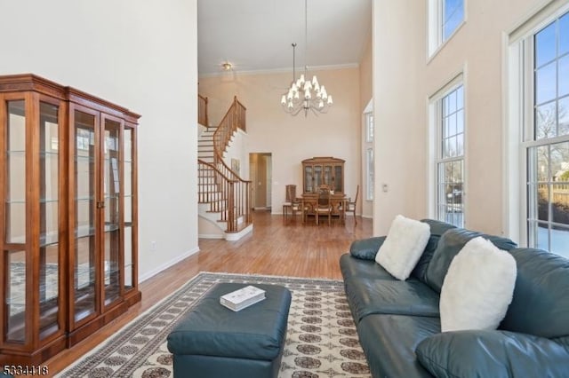 living room featuring hardwood / wood-style flooring, a wealth of natural light, a chandelier, and a towering ceiling