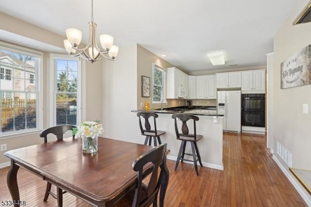 dining room with sink, hardwood / wood-style floors, and a notable chandelier