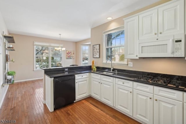 kitchen with black appliances, kitchen peninsula, and white cabinets