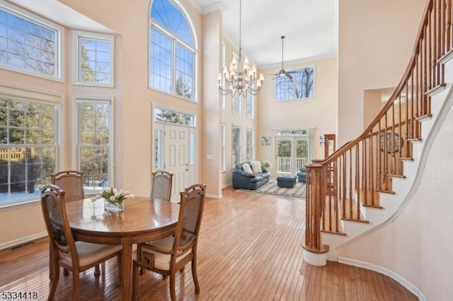 dining area featuring a high ceiling, crown molding, an inviting chandelier, and light hardwood / wood-style flooring