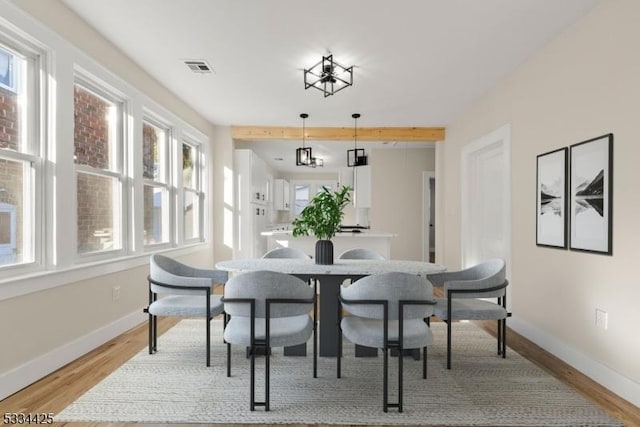 dining space with beam ceiling and light hardwood / wood-style flooring