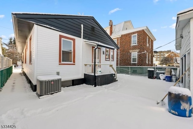 snow covered rear of property featuring cooling unit