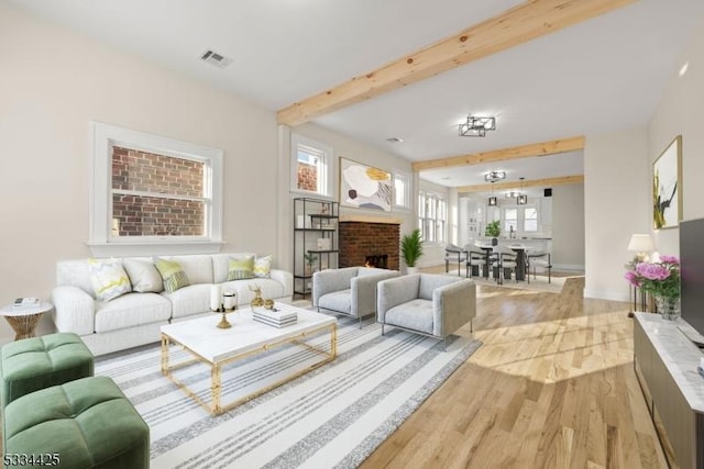 living room with a fireplace, beamed ceiling, and light wood-type flooring