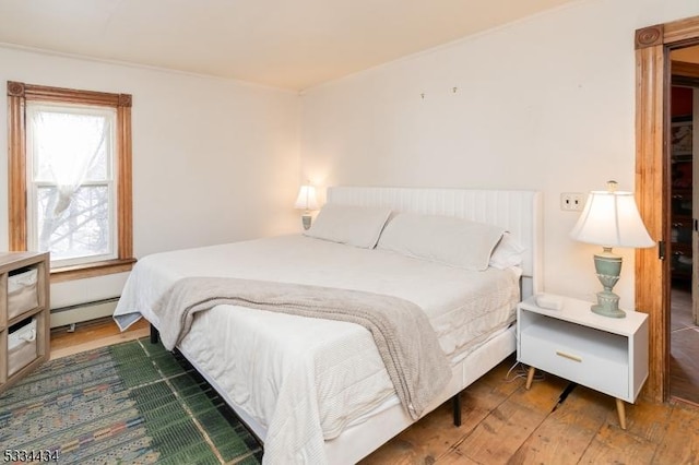 bedroom with a baseboard radiator and dark hardwood / wood-style floors