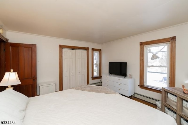 bedroom with baseboard heating, ornamental molding, and a closet