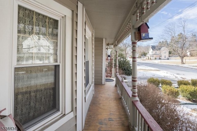 snow covered back of property featuring covered porch