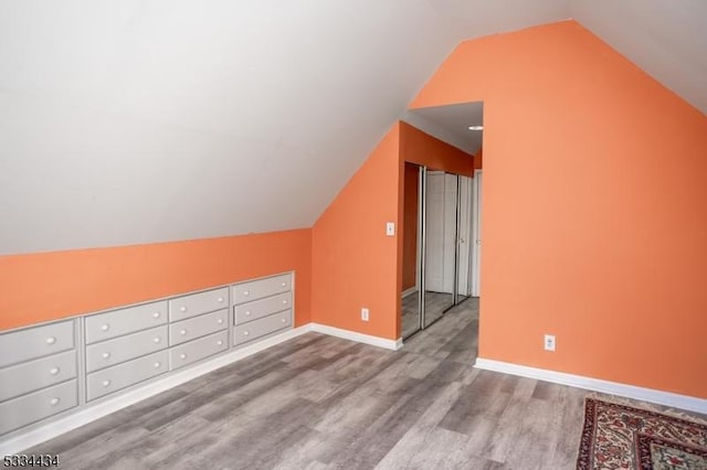 additional living space featuring lofted ceiling and light hardwood / wood-style floors