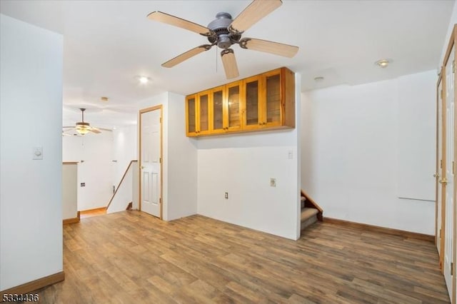 empty room with ceiling fan, stairway, and wood finished floors