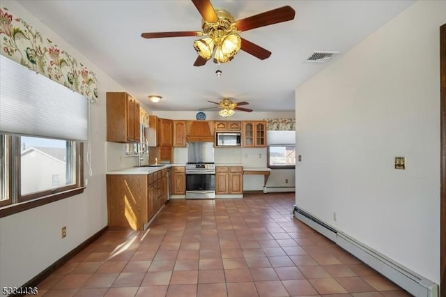 kitchen featuring visible vents, brown cabinetry, baseboard heating, light countertops, and stainless steel range with gas stovetop