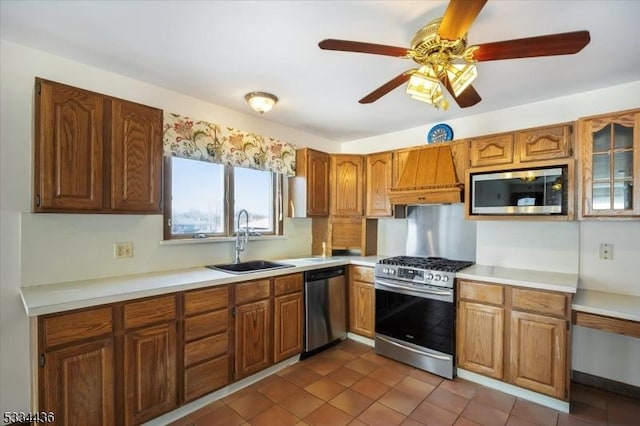 kitchen with appliances with stainless steel finishes, brown cabinets, custom exhaust hood, light countertops, and a sink