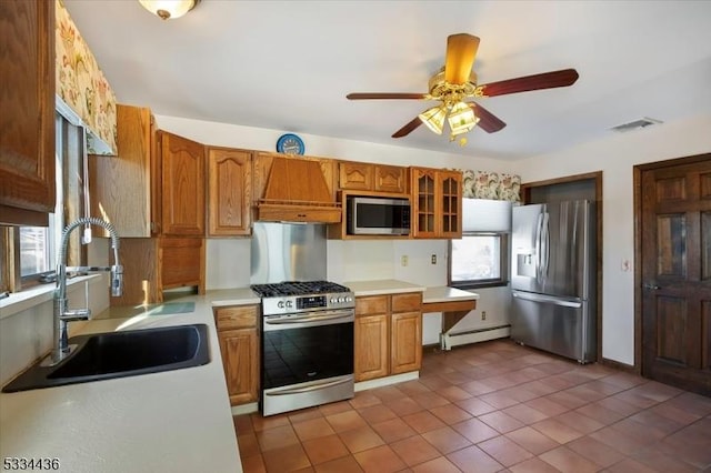 kitchen featuring baseboard heating, stainless steel appliances, light countertops, dark tile patterned floors, and a sink